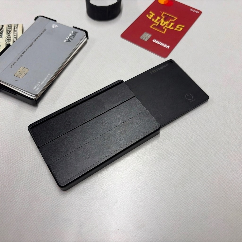 The rechargeable tracking card sliding into the Brik metal wallet